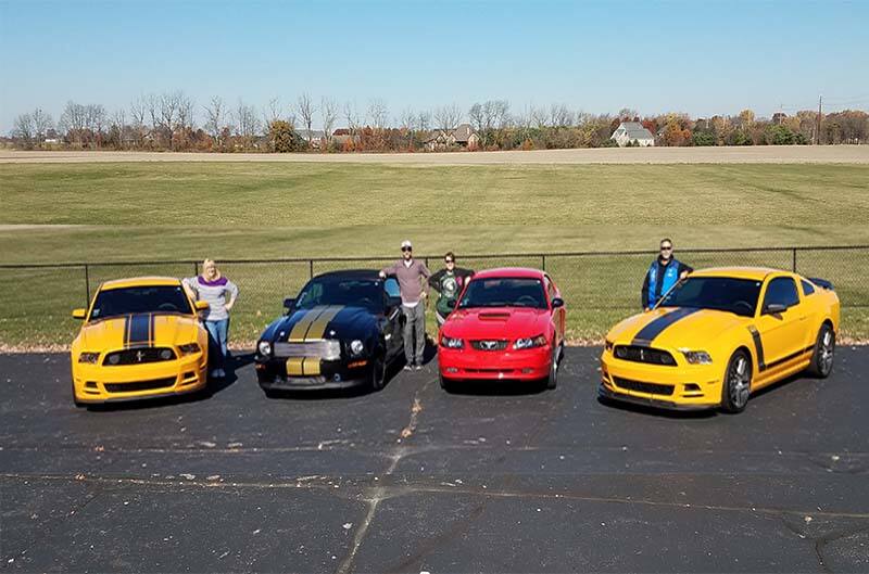 Family Standing next to Mustangs